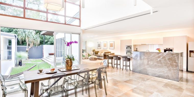A large dining area, kitchen and living room looking out onto a garden